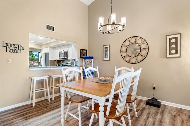 dining space with crown molding, light hardwood / wood-style floors, a chandelier, and a high ceiling