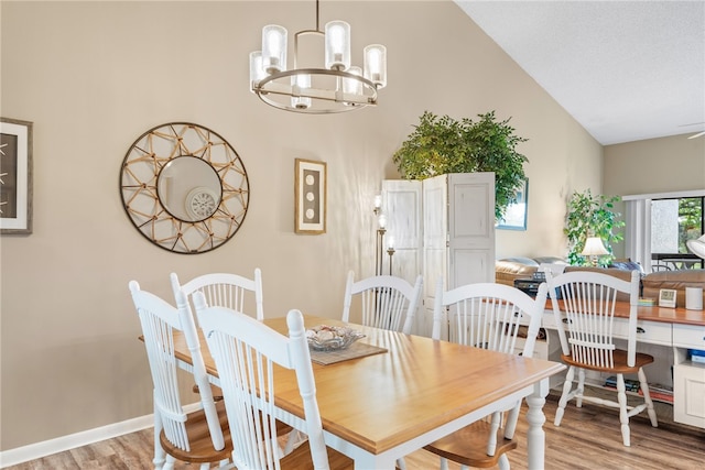 dining area featuring light hardwood / wood-style floors, a chandelier, and high vaulted ceiling