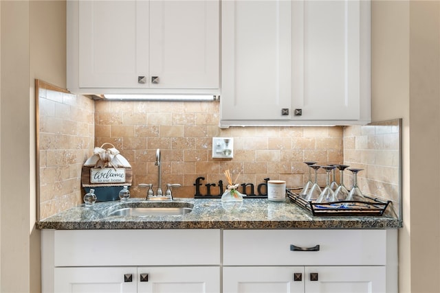 kitchen with white cabinets, dark stone countertops, sink, and decorative backsplash