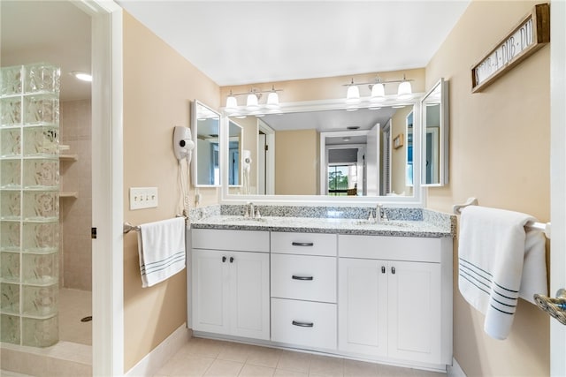 bathroom with tiled shower, vanity, and tile patterned floors