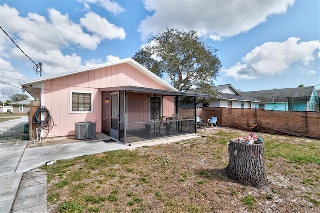 rear view of property with a sunroom, cooling unit, a patio area, and a lawn