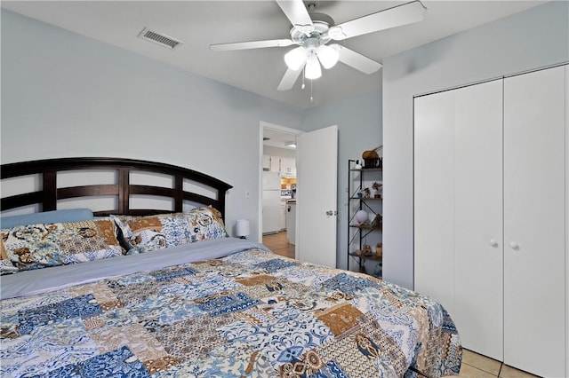 tiled bedroom featuring a closet, ceiling fan, and white fridge