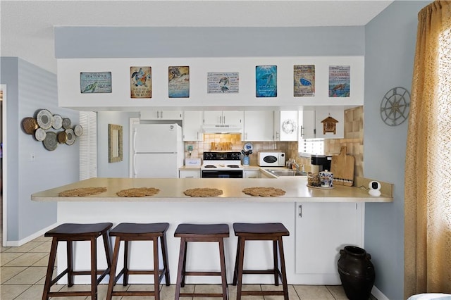 kitchen with white refrigerator, a kitchen breakfast bar, kitchen peninsula, range with electric cooktop, and white cabinets