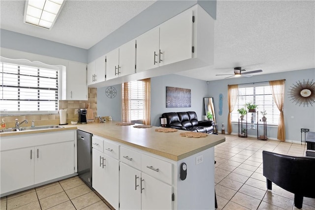 kitchen with sink, dishwasher, white cabinetry, tasteful backsplash, and kitchen peninsula