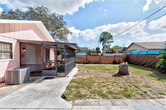 view of yard with a patio, a sunroom, and central air condition unit