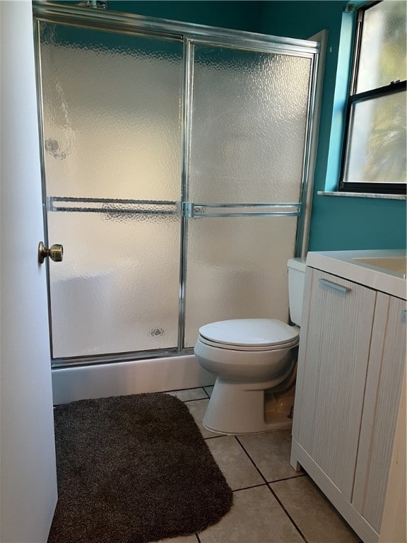 bathroom featuring vanity, a shower with door, tile patterned flooring, and toilet