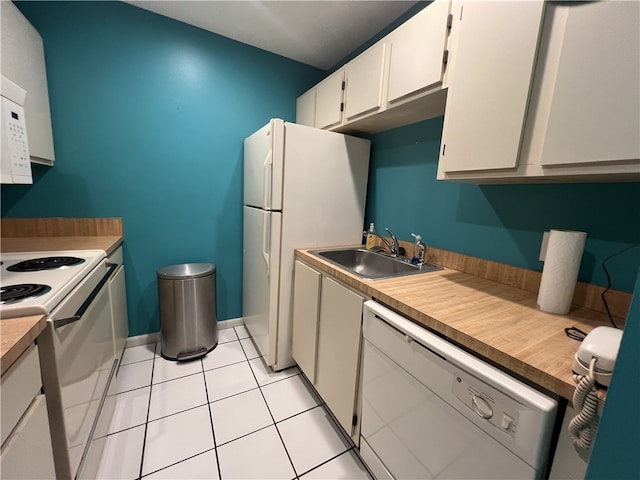 kitchen with white appliances, sink, light tile patterned floors, and white cabinets