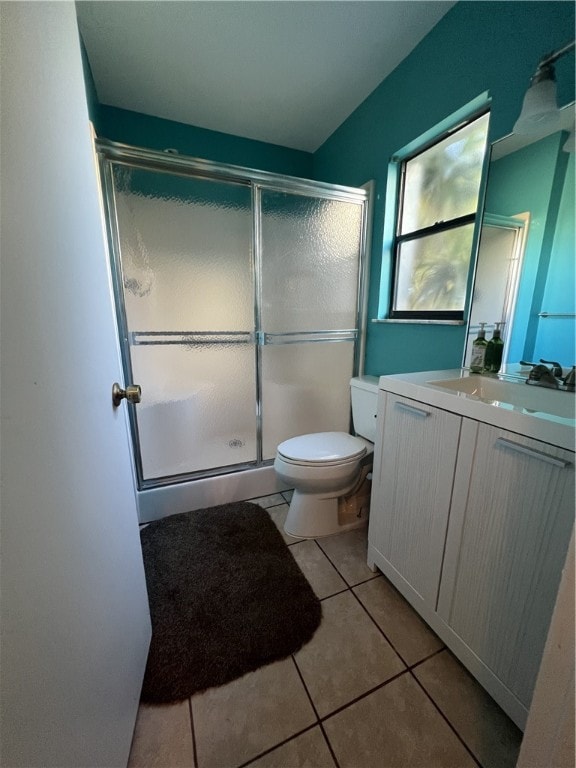 bathroom with toilet, vanity, tile patterned floors, and a shower with shower door