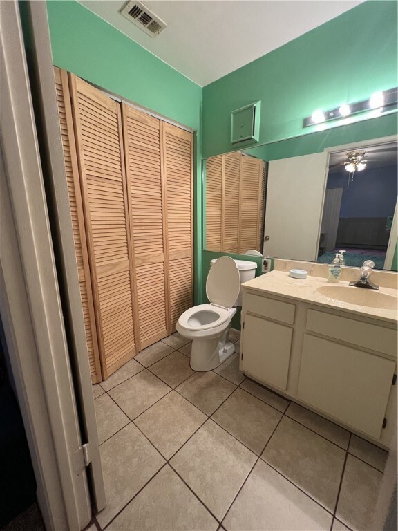 bathroom with toilet, vanity, ceiling fan, and tile patterned floors