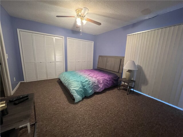 bedroom featuring carpet flooring, a textured ceiling, ceiling fan, and two closets