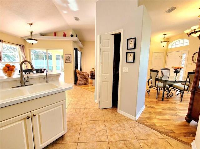 kitchen with vaulted ceiling, light tile patterned flooring, sink, hanging light fixtures, and an inviting chandelier