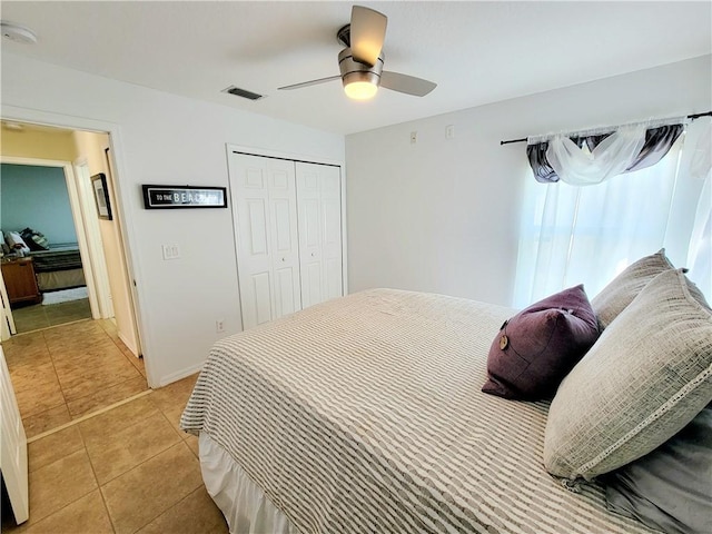 bedroom featuring light tile patterned floors, ceiling fan, and a closet