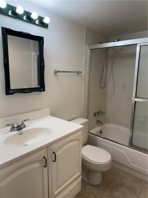 full bathroom featuring bath / shower combo with glass door, toilet, vanity, and tile patterned flooring