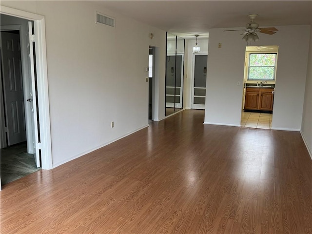 empty room featuring visible vents, light wood-style floors, and ceiling fan