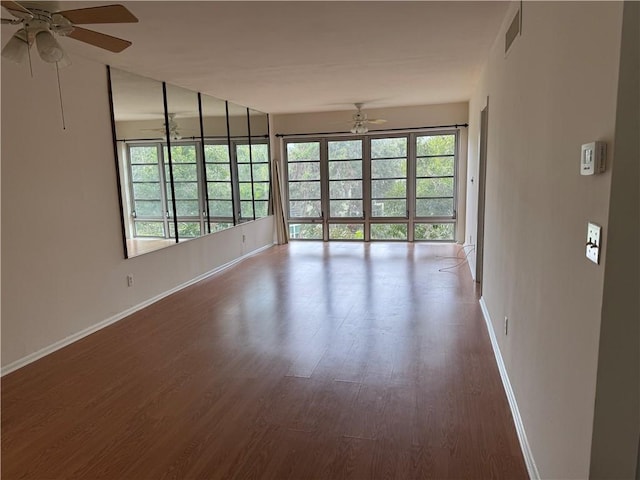 spare room with baseboards, wood finished floors, visible vents, and ceiling fan