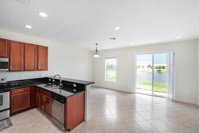 263 Provence Pl, Vero Beach, FL 32960 - kitchen with stainless steel appliances, a peninsula, plenty of natural light, a textured ceiling, and dark stone countertops