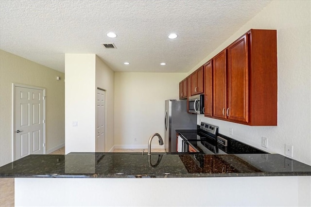 263 Provence Pl, Vero Beach, FL 32960 - kitchen with stainless steel appliances, dark stone countertops, a peninsula, a textured ceiling, and recessed lighting