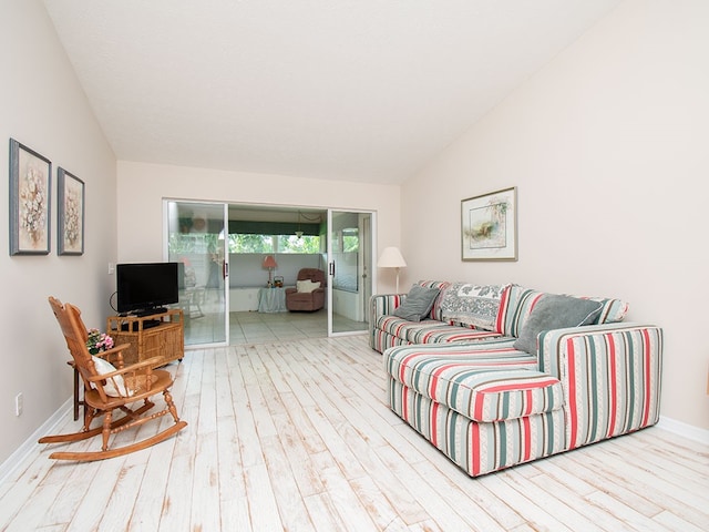 living area featuring lofted ceiling, wood finished floors, and baseboards