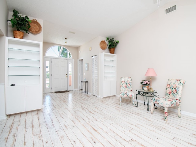 foyer entrance with baseboards, visible vents, and light wood finished floors