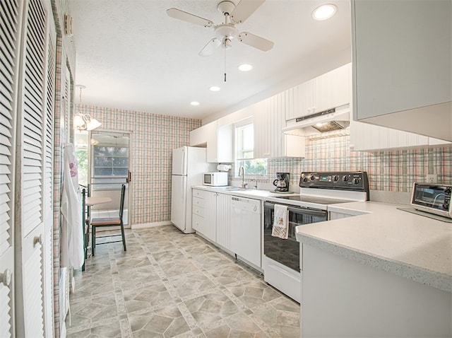 kitchen with light countertops, white cabinets, white appliances, under cabinet range hood, and wallpapered walls