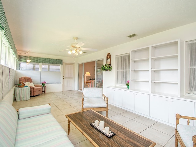 living room with light tile patterned floors, visible vents, and a ceiling fan