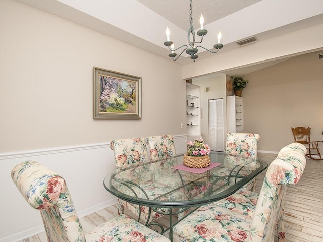 dining space featuring a chandelier, visible vents, baseboards, and wood finished floors