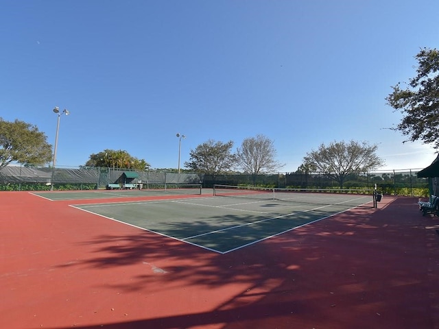 view of tennis court featuring community basketball court and fence