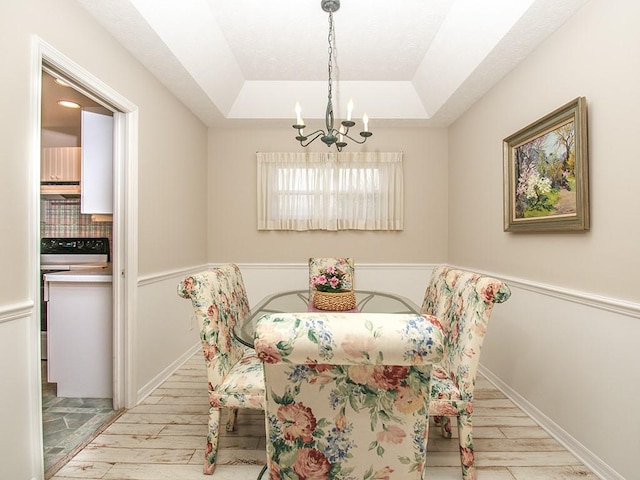 dining area with a notable chandelier, a tray ceiling, and wood finished floors