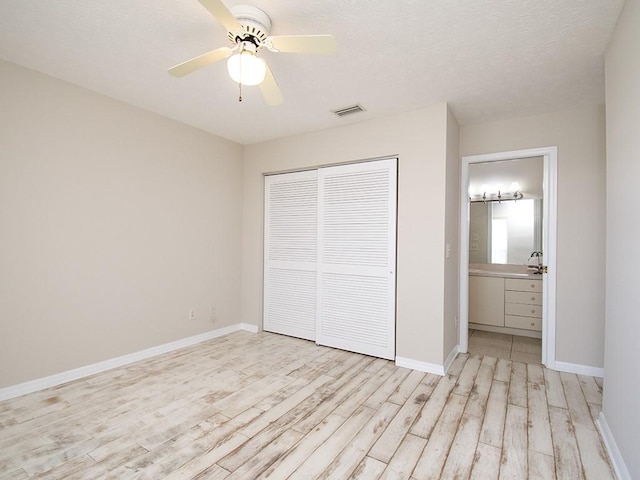 unfurnished bedroom featuring baseboards, light wood-style flooring, visible vents, and a closet