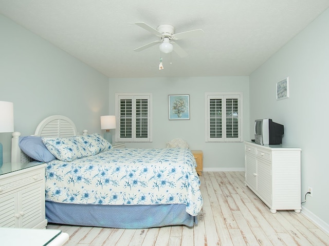 bedroom featuring ceiling fan, light wood-style flooring, and baseboards