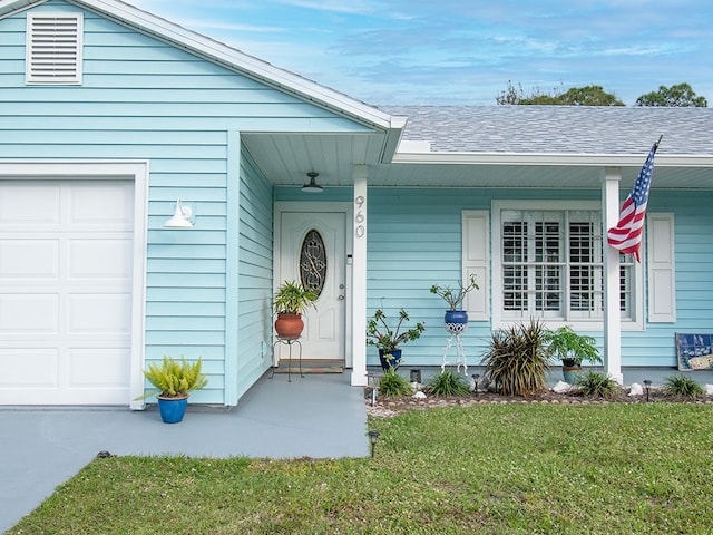 entrance to property with a garage and a lawn