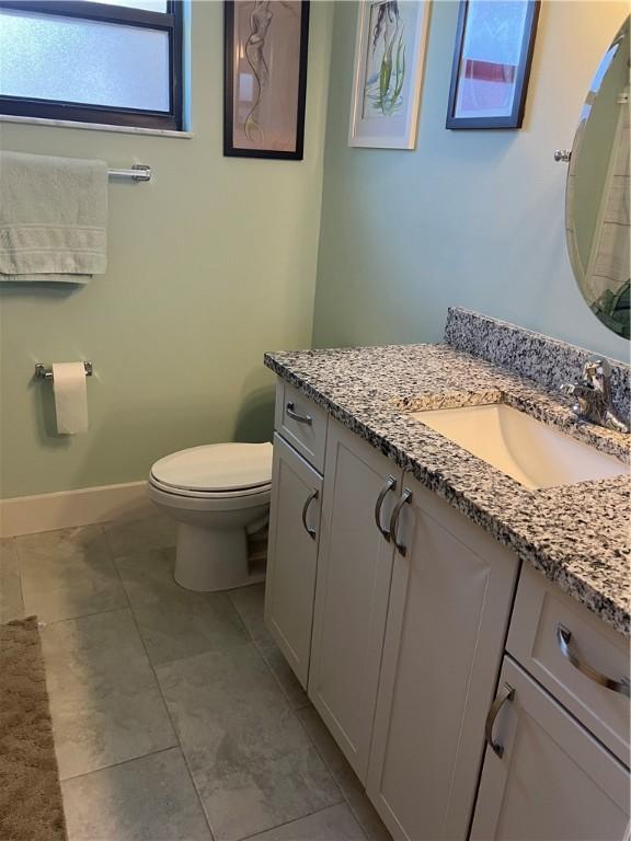 bathroom featuring vanity, baseboards, toilet, and tile patterned flooring