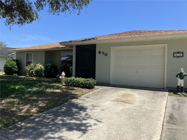single story home with concrete driveway, an attached garage, a front yard, and stucco siding