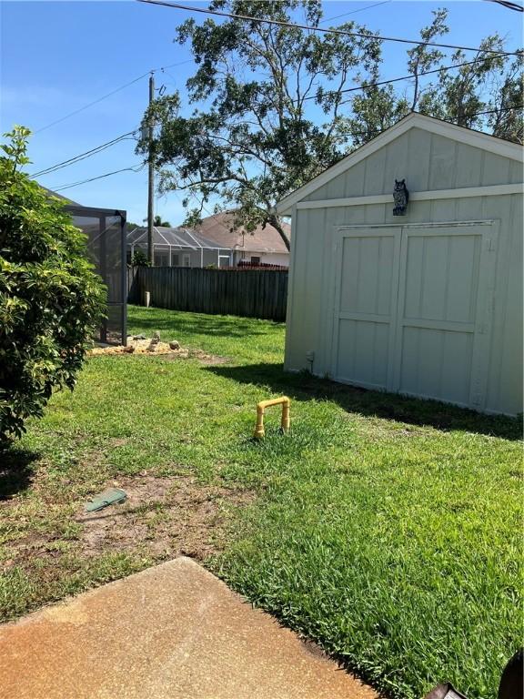 view of yard featuring a storage unit, fence, and an outbuilding