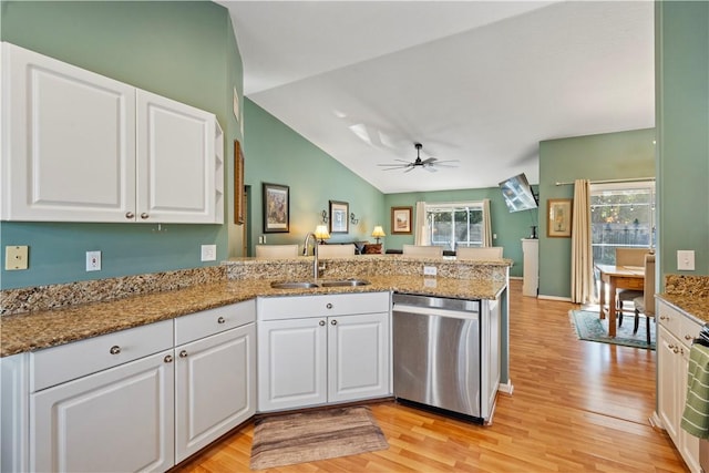 kitchen with stainless steel dishwasher, a peninsula, white cabinets, and a sink