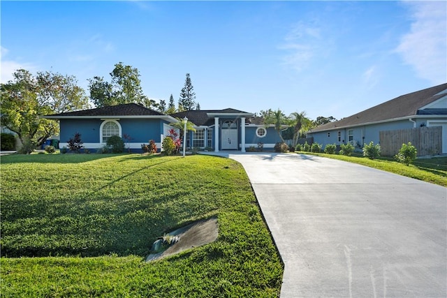 ranch-style home with a front yard, fence, and driveway