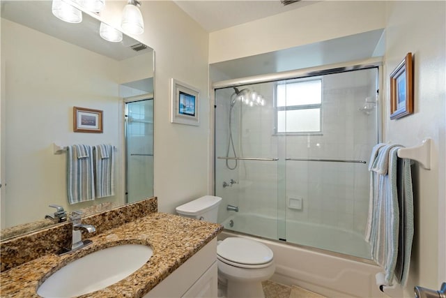 bathroom with combined bath / shower with glass door, toilet, and vanity