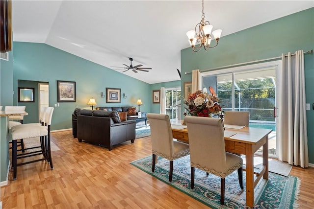 dining area with ceiling fan with notable chandelier, vaulted ceiling, baseboards, and light wood-type flooring