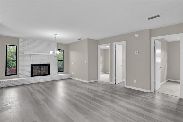 unfurnished living room with a fireplace, light wood-type flooring, and a wealth of natural light