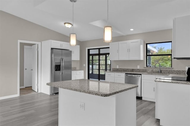 kitchen with white cabinets, appliances with stainless steel finishes, decorative light fixtures, and plenty of natural light