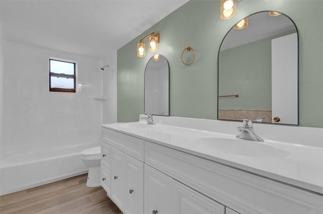 full bathroom featuring hardwood / wood-style floors, vanity, tiled shower / bath combo, and toilet