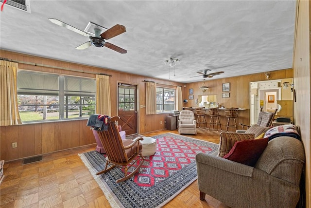 living room with light parquet floors and wooden walls