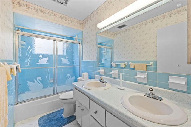 full bathroom featuring toilet, combined bath / shower with glass door, tile walls, tile patterned floors, and vanity