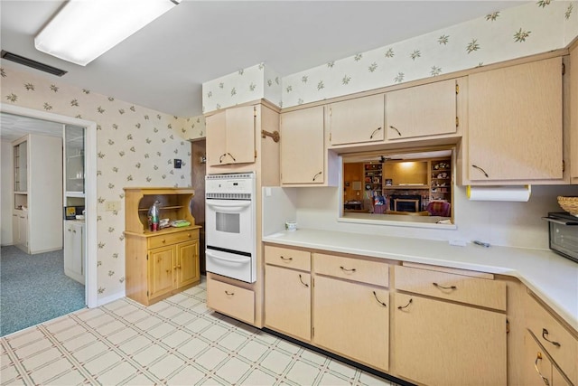 kitchen with light brown cabinetry, light carpet, and oven