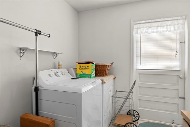 laundry room featuring washer and clothes dryer and cabinets