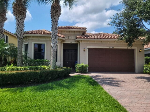 4295 55th St, Vero Beach, FL 32967 - mediterranean / spanish-style home with an attached garage, decorative driveway, stucco siding, a tiled roof, and a front lawn