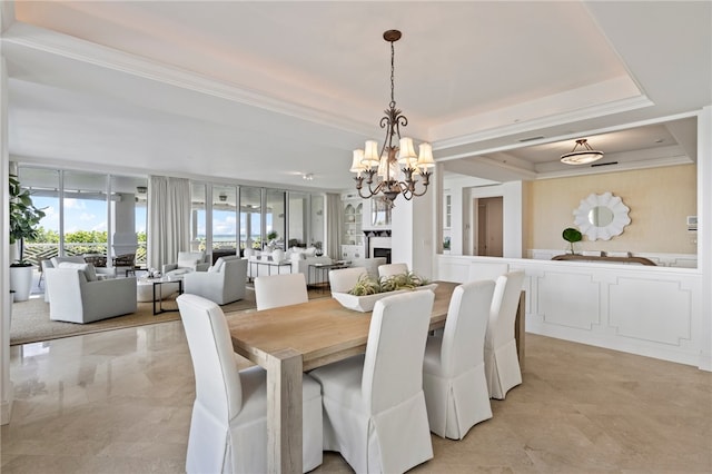 dining area with a chandelier, a raised ceiling, and crown molding