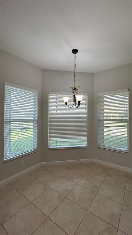 unfurnished dining area with a chandelier and light tile patterned floors