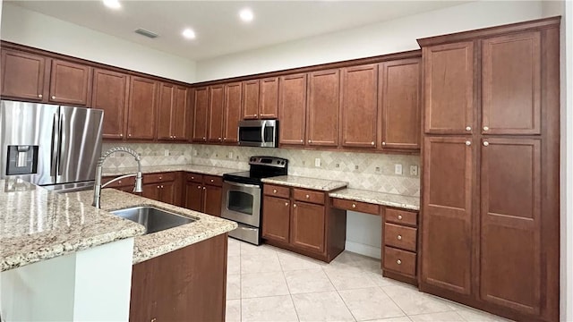 kitchen featuring sink, appliances with stainless steel finishes, backsplash, light stone countertops, and light tile patterned flooring