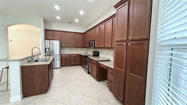 kitchen with sink, backsplash, a kitchen bar, stainless steel appliances, and light stone countertops